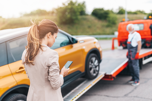 Roadside assistance technician helping a stranded driver with a jump start and flat tire in Pasadena, TX