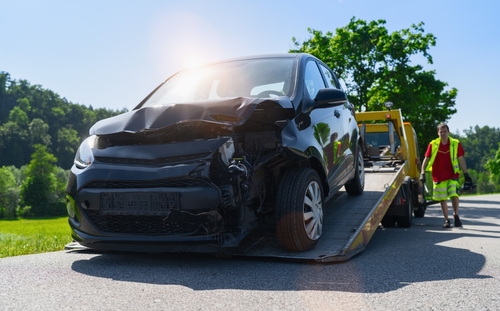 Roadside assistance technician helping a stranded driver with a jump start and flat tire in South Houston, TX