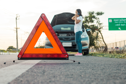 Roadside assistance technician helping a driver with a jump start and flat tire in The Woodlands, TX